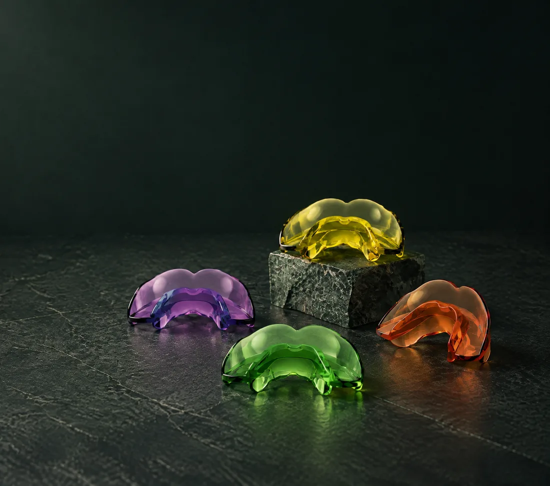Bioactivadores AMCOP de silicona translúcida en violeta, amarillo, naranja y verde sobre pizarra oscura